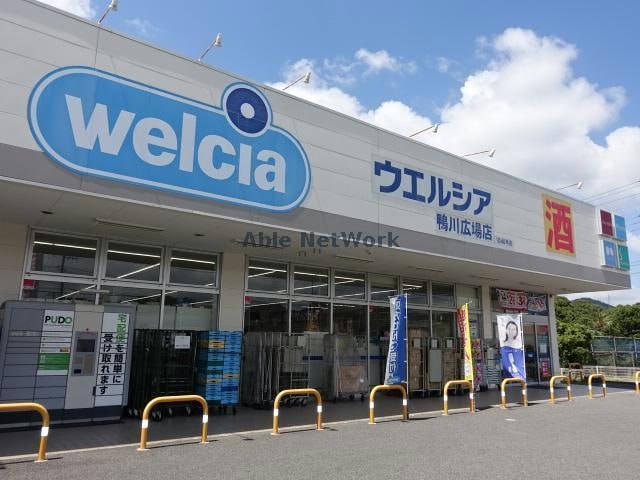 ウエルシア鴨川広場店(ドラッグストア)まで1022m ガネーシャ弐番館