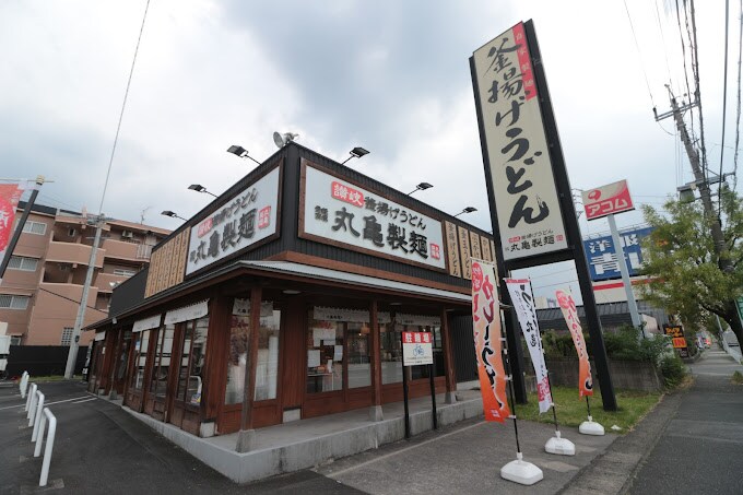丸亀製麺 鴻仏目店(その他飲食（ファミレスなど）)まで610m プランドールⅢ